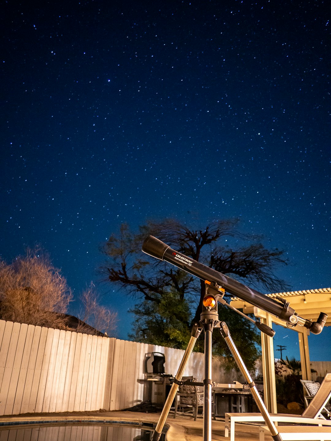 Telescope pointed at the starry night sky in a backyard.